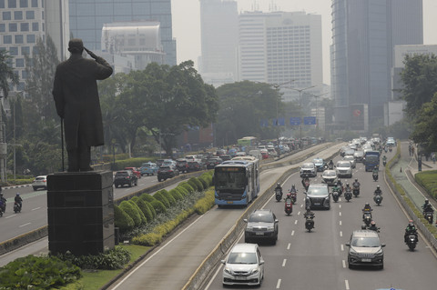Sejumlah kendaraan melintas dengan latar belakang gedung yang diselimuti polusi udara di Jalan Sudirman, Jakarta, Kamis (26/6/2025). Foto: Jamal Ramadhan/kumparan