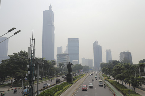 Sejumlah kendaraan melintas dengan latar belakang gedung yang diselimuti polusi udara di Jalan Sudirman, Jakarta, Kamis (26/6/2025). Foto: Jamal Ramadhan/kumparan