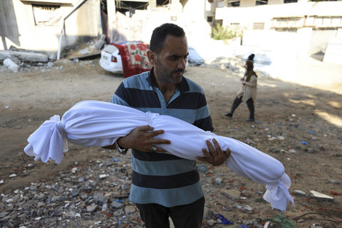 Seorang pria membawa jenazah seorang anak di Gaza, Rabu (25/6/2025). Foto: Dawoud Abu Alkas/REUTERS