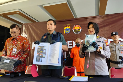 Polisi menujukkan tersangka dan barang bukti ojek online berinisial AS (38 tahun) yang menipu ratusan orang dengan berpura-pura jadi pegawai OJK dan mengaku bisa hapuskan utang pinjol, Kamis (26/6/2025). Foto: Arfiansyah Panji Purnandaru/kumparan