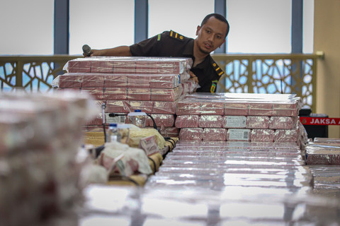 Petugas menumpuk uang barang bukti saat Konferensi Pers di Gedung Bundar Kejaksaan Agung RI, Jakarta, Rabu (2/7/2025). Foto: Iqbal Firdaus/kumparan