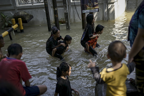 Sejumlah warga melintas saat banjir di kawasan Bidaracina, Jatinegara, Jakarta Timur, Minggu (6/7/2025). Foto: Jamal Ramadhan/kumparan