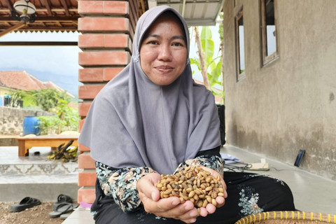 Titi saat menunjukkan biji kopi miliknya, Minggu (6/7/2025). Foto: kumparan