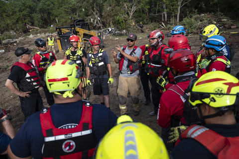 Kru petugas pemadam kebakaran dari Ciudad Acuna, Meksiko, berkumpul untuk briefing saat mereka membantu upaya pencarian dan penyelamatan di dekat Sungai Guadalupe setelah banjir bandang melanda daerah tersebut pada Senin (7/8/2025). Foto: Eli Hartman/AP Photo