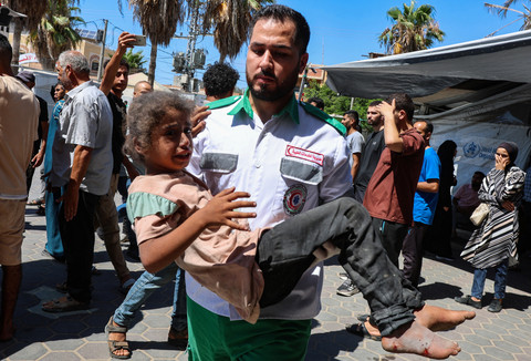 Seorang warga Palestina menggendong seorang anak saat warga Palestina yang terluka menerima perawatan di Rumah Sakit Syuhada Al-Aqsa, setelah serangan udara Israel terhadap sebuah rumah, di Deir al-Balah, Jalur Gaza tengah, 8 Juli 2025. Foto: REUTERS/Ramadan Abed