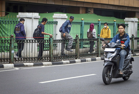 Sejumlah warga melompati pagar pembatas jalan di Stasiun Cikini, Jakarta, Jumat (11/7/2025). Foto: Iqbal Firdaus/kumparan