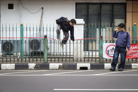 Seorang warga melompati pagar pembatas jalan di Stasiun Cikini, Jakarta, Jumat (11/7/2025). Foto: Iqbal Firdaus/kumparan