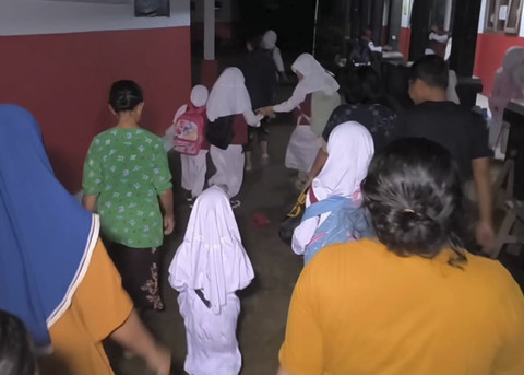 Orang tua murid dan murid saat hendak masuk ke sekolah menunggu penjaga sekolah membuka gerbang di SD Negeri 4 Kedokanagung, Kecamatan Kedokan Bunder, Kabupaten Indramayu, Senin (14/7/2025). Foto: kumparan