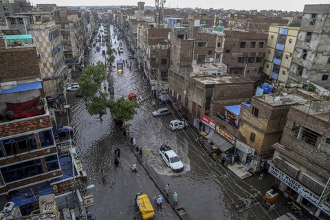 Para komuter melewati jalan yang tergenang air saat hujan monsun lebat di Hyderabad, di provinsi Sindh, Pakistan, Senin (14/7/2025). Foto: Husnain Ali/AFP