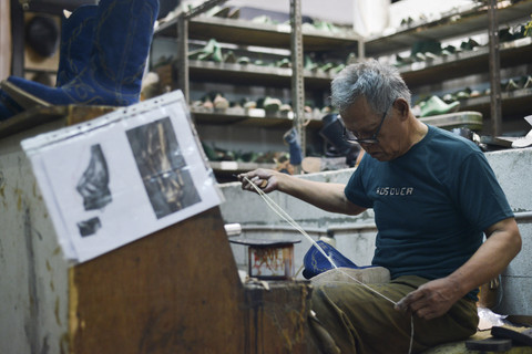 Seorang pengrajin mengerjakan sepasang sepatu bot kulit untuk pasar AS di bengkel Tegep Boots di Bandung, Jawa Barat, Selasa (15/7/2025). Foto: TIMUR MATAHARI/AFP