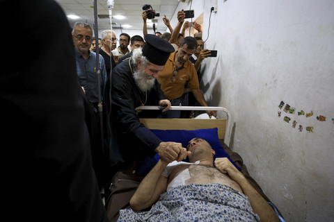 Seorang anggota ulama memegang tangan seorang warga Palestina yang terluka saat mengunjungi Rumah Sakit Arab Al-Ahli di Gaza, Jumat (18/7/2025). Foto: Dawoud Abu Alkas/REUTERS