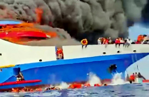 Para penumpang yang berusaha melompat dari atas kapal KM Barcelona yang terbakar di perairan Talise, Minggu (20/7). (foto: video fb)