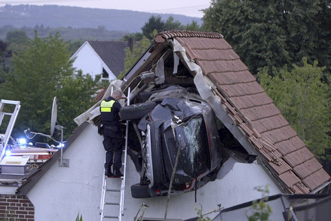 Seorang petugas polisi memeriksa sebuah mobil yang tersangkut di dinding gudang setelah kecelakaan di Bohmte, Jerman, Minggu (20/7/2025). Foto: Torben Kipp/DPA via AP