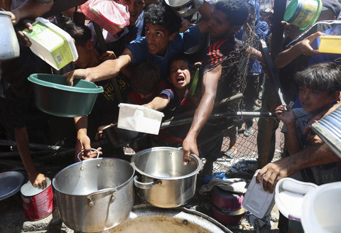 Warga Palestina dan ana-anak berkumpul untuk menerima makanan dari dapur umum, di tengah krisis kelaparan, di Nuseirat, Jalur Gaza tengah, Senin (20/7/2025). Foto: Ramadan Abed/REUTERS