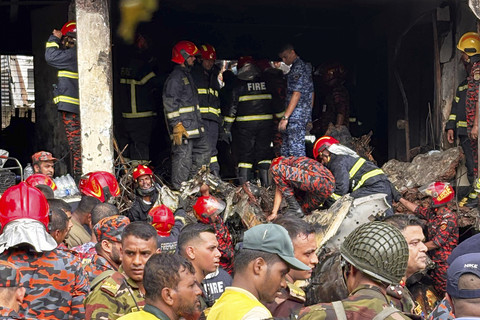 Petugas pemadam kebakaran memeriksa puing-puing pesawat latih Angkatan Udara Bangladesh yang jatuh di kampus sekolah di Dhaka, Bangladesh, Senin (21/7/2025). Foto: Al-emrun Garjon/AP Photo