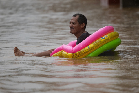 Seorang pria menggunakan kolam renang tiup untuk anak-anak melewati daerah yang terendam banjir setelah hujan monsun di Cainta, Rizal, Filipina, Selasa (22/7/2025). Foto: Eloisa Lopez/REUTERS