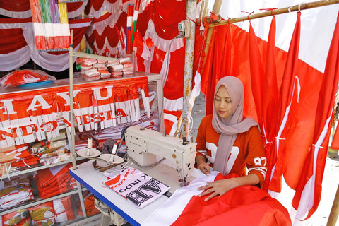 Hamidah, pedagang bendera saat menjahit beberapa bendera pesanan pelanggan untuk kebutuhan hiasan HUT RI ke 80 di kampung bendera Darmokali Surabaya (22/7). FOTO: DIPTA WAHYU