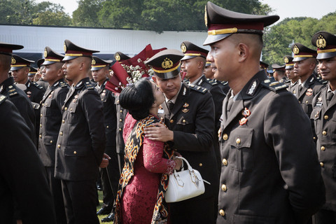 Perwira remaja dari Polri dicium oleh ibunya usai Upacara Prasetya Perwira (Praspa) TNI dan Polri tahun 2025 di halaman Istana Merdeka, Jakarta, Rabu (23/7/2025). Foto: Yasuyoshi Chiba/AFP