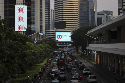 Sejumlah kendaraan melintas di dekat Videotron yang menampilkan logo HUT RI ke-80 di kawasan Jalan Sudirman, Jakarta, Kamis (24/7/2025). Foto: Iqbal Firdaus/kumparan