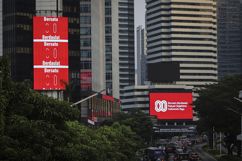 Sejumlah kendaraan melintas di dekat Videotron yang menampilkan logo HUT RI ke-80 di kawasan Jalan Sudirman, Jakarta, Kamis (24/7/2025). Foto: Iqbal Firdaus/kumparan