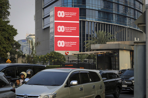 Sejumlah kendaraan melintas di dekat Videotron yang menampilkan logo HUT RI ke-80 di kawasan Jalan Sudirman, Jakarta, Kamis (24/7/2025). Foto: Iqbal Firdaus/kumparan