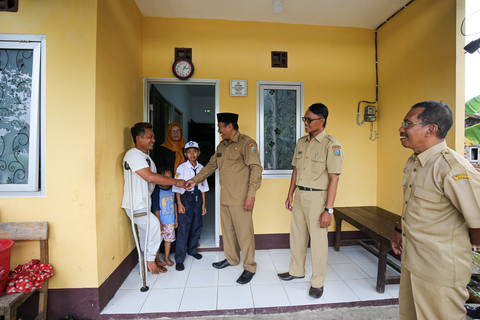 Huda berjabat tangan dengan Kades Karangmalang, Masyhuri, di depan rumahnya yang telah direnovasi. Foto: Aditia Noviansyah/kumparan