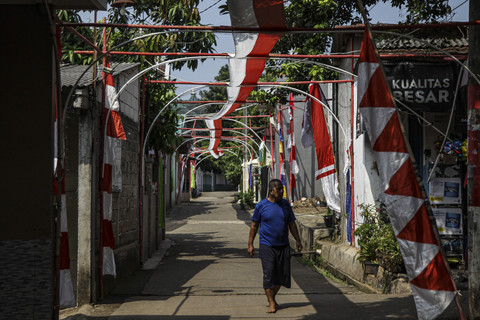 Warga melintas di bawah bendera Merah Putih sepanjang 1 kilometer di Kelurahan Mustikjaya, Bekasi, Jawa Barat, Selasa (5/8/2025). Foto: Darryl Ramadhan/kumparan