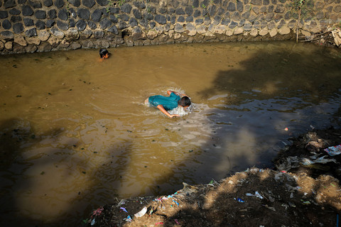 Anak-anak Desa Kesambi bermain di sungai yang kotor. Sebelum program sanitasi aman digencarkan, banyak warga yang membuang tinja ke sungai. Foto: Aditia Noviansyah/kumparan