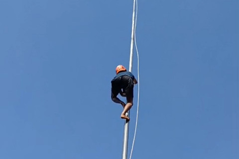 Sulasmono Mahmud saat memanjat tiang untuk mengambil tali bendera yang nyangkut di Alun-Alun Kabupaten Lumajang. Foto: Dok. Istimewa