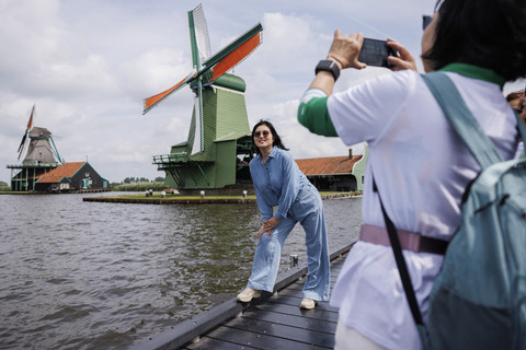 Sejumlah warga berswafoto dengan latar belakang kincir angin Zaanse Schan di Belanda, Kamis (31/7/2025). Foto: Simon Wohlfahrt/AFP
