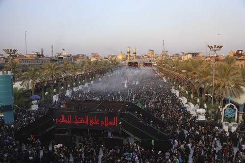 Umat Syiah berkumpul di antara makam Imam Abu Al-Fadl Al-Abbas (latar belakang) dan Imam Hussein (tidak terlihat) di kota suci Karbala, Irak (24/8/2024). Foto: MOHAMMED SAWAF/AFP