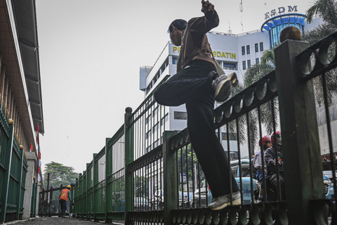 Warga melompati pagar saat berlangsungnya proyek peninggian pagar di Stasiun Cikini, Jakarta, Senin (11/8/2025). Foto: Sulthony Hasanuddin/ANTARA FOTO