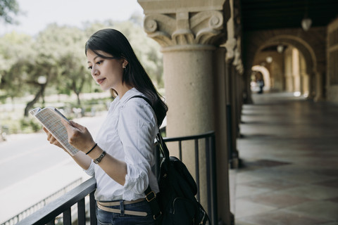 Seorang mahasiswi membaca buku di luar kelas. Foto: Shutterstock