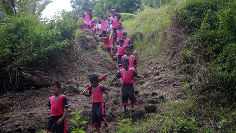 Anak-anak SD Negeri Airbanua kelas jarak jauh di Desa Wawonian, Kecamatan Barat, Kabupaten Utara (Minut), (Sulut), berjalan melewati medan curam untuk menuju ke sekolah mereka. (foto: febry kodongan)