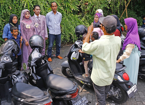 Sepasang pengantin berfoto bersama sanak keluarga yang hadir dalam prosesi nikah massal