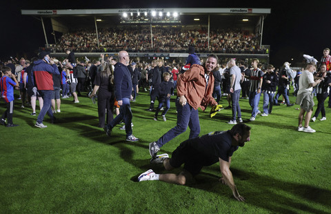 Sejumlah suporter klub sepak bola Grimsby Town masuk ke dalam lapangan saat berselebrasi usai mengalahkan Manchester United pada pertandingan ronde kedua Piala Liga Inggris di Blundell Park, Cleethorpes, Inggris, Rabu (28/8/2025). Foto: Lee Smith/Reuters