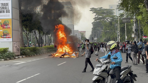 Massa membakar sejumlah barang dari banner hingga barrier plastik di tengah-tengah Jalan Asia Afrika, Kamis (28/8/2025). Foto: Abid Raihan/kumparan