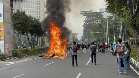 Massa membakar sejumlah barang dari banner hingga barrier plastik di tengah-tengah Jalan Asia Afrika, Kamis (28/8/2025). Foto: Abid Raihan/kumparan