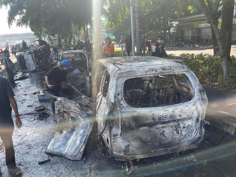 Pengunjuk rasa mengambil sisa-sisa besi dari mobil yang hangus terbakar saat aksi di kawasan Mako Brimob Kwitang, Jakarta, Jumat (29/8/2025). Foto: Darryl Ramadhan/kumparan