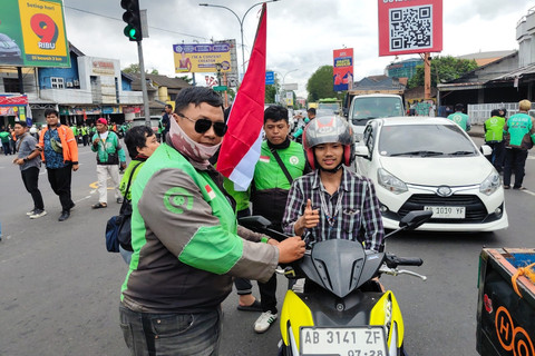 Ojol bagi-bagi pita hitam sebagai bentuk solidaritas untuk Affan Kurniawan, ojol yang dilindas rantis polisi saat demo di Jakarta di perempatan Condongcatur, Kabupaten Sleman, Jumat (29/8/2025). Foto: Arfiansyah Panji Purnandaru/kumparan