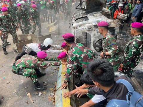 Sejumlah petugas TNI bersama massa aksi dan warga mengevakuasi kendaraan yang hangus terbakar saat aksi di kawasan Mako Brimob Kwitang, Jakarta, Jumat (29/8/2025). Foto: Darryl Ramadhan/kumparan