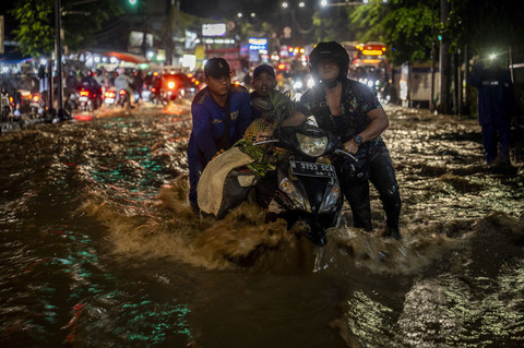 Petugas bersama warga membantu pengendara motor menerobos luapan Kali Baru di Jalan Raya Bogor, Kramat Jati, Jakarta, Jumat (29/8/2025). Foto: Bayu Pratama S/ANTARA FOTO