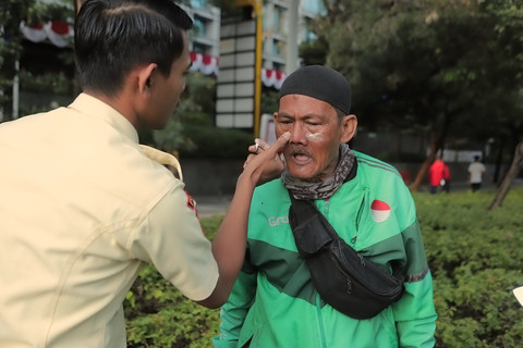 Satpam perkantoran dan sopir ojek online (ojol) membantu memberikan air bersih kepada para pengendara yang terkena sisa gas air mata di kawasan Polda Metro Jaya, Jakarta, Sabtu (30/8/2025). Foto: Iqbal Firdaus/kumparan