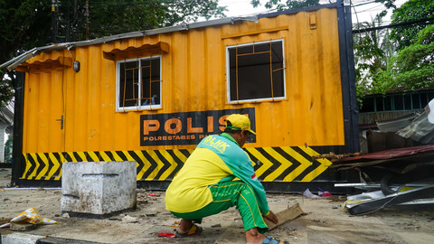 Seorang pekerja yang membersihkan Puing-puing bangunan pos polisi di kawasan simpang lima DPRD Sumsel yang menjadi sasaran aksi anarkis, Minggu (31/8) Foto: abp/urban id