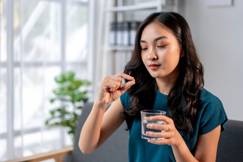 Perempuan minum vitamin. Foto: Shutterstock