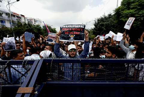 Para demonstran yang membawa plakat berdiri di balik barikade selama protes menentang korupsi dan keputusan pemerintah untuk memblokir beberapa platform media sosial, di Kathmandu, Nepal, Senin (8/9/2025). Foto: Navesh Chitrakar/REUTERS