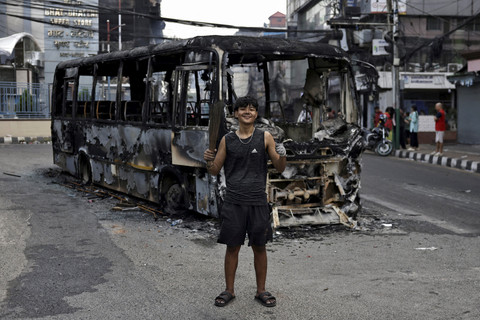 Seorang pelajar, Karan Kulung (18) berpose di depan bus terbakar saat mengikuti aksi menentang korupsi di Kathmandu, Nepal. Foto: Navesh Chitrakar/Reuters