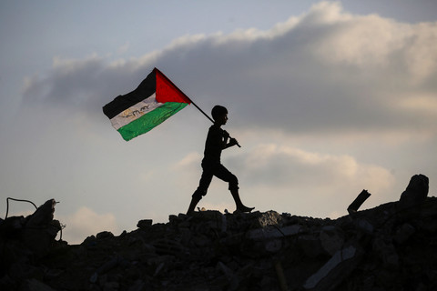 Seorang anak mengibarkan bendera Palestina di atas reuntuhan bangunan di kamp pengungsi Bureij, Jalur Gaza tengah, Senin (22/9/2025). Foto: Eyad BABA / AFP