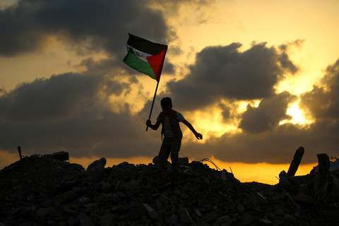 Seorang anak mengibarkan bendera Palestina di atas reuntuhan bangunan di kamp pengungsi Bureij, Jalur Gaza tengah, Senin (22/9/2025). Foto: Eyad BABA / AFP