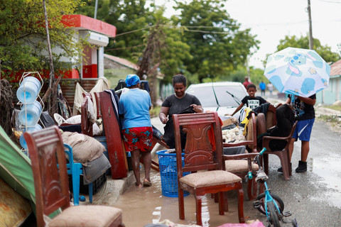 Warga mengevakuasi barang-barang mereka setelah badai tropis menyebabkan Sungai Tabara meluap dan membanjiri rumah-rumah di El Rosario, Provinsi Azua, Republik Dominika, Jumat (26/9/2025). Foto: Erika Santelices/REUTERS